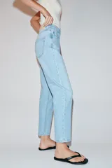 Pantalón jeans Z1975 de tiro alto y diseño mom fit, color azul claro con lavado desgastado, de corte tobillero y cinco bolsillos. Cierre frontal con cremallera y botón metálico.