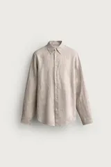 Camisa de lino color beige, de corte regular fit, con cuello abotonado, manga larga y cierre frontal de botonadura.