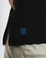 Buzo de lana merino con cuello bote y mangas largas. Presenta un detalle bordado a mano en color azul en la parte inferior.