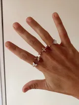 Anillo ajustable de metal dorado con dije de cruz decorado con pequeños cristales brillantes.