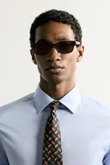 Corbata ancha de seda jacquard color azul marino, con estampado de pelotas de rugby en tonos marrón y verde.