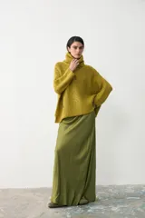 Sweater tipo poncho de tejido de punto grueso, color verde oliva, con cuello alto holgado y diseño de caída amplia.