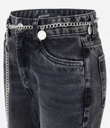 Pantalón de jean modelo flare de tiro alto, con cierre frontal de botón y cremallera, bolsillos laterales y traseros. Incluye un cinturón de cadena metálica con dijes colgantes.