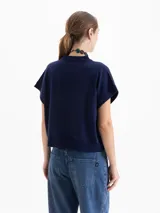 Chaleco de tejido de punto en color celeste, con cuello redondo y mangas cortas con terminación en rib. Presenta un diseño holgado con aberturas laterales en el ruedo y un pequeño bordado decorativo en la parte inferior.