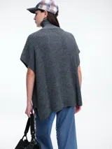 Chaleco tipo poncho de tejido de punto color tostado, con cuello polera y diseño holgado con laterales abiertos.