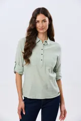 Camisa de lino lisa color celeste, de manga larga con puños abotonados y trabilla para arremangar. Cuenta con cuello clásico, cierre frontal con botones y bolsillos plaqué en el pecho.