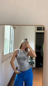 Top sin mangas de cuello redondo, confeccionado en tejido tipo jersey elastizado con acabado metalizado plateado.