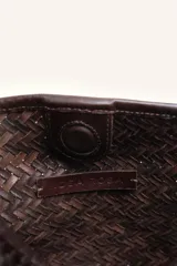Cartera tipo morral y bandolera de cuero vacuno marrón, completamente trenzada a mano con diseño estructurado y correa larga trenzada.