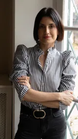 Camisa de rayas verticales en blanco y negro, con cuello alto tipo volante y mangas abullonadas con frunces en los hombros.