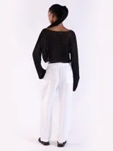 Sweater crop negro de punto abierto y manga larga con brillo sutil. Presenta escote bote y diseño relajado.