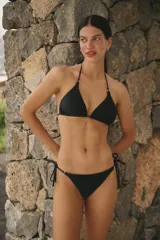 Conjunto de bikini negro de lycra mate, con corpiño triangular y bombacha vedetina con tiras laterales regulables.