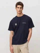 Camiseta de manga corta en color azul marino, con cuello redondo y corte clásico. Presenta un pequeño estampado en el pecho que incluye el logo de la marca y una cruz dentro de un cuadrado.
