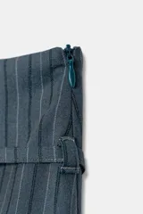 Falda pantalón de tiro medio con diseño de rayas verticales. Presenta un cinturón fino integrado con hebilla metálica y cierre lateral con cremallera oculta.