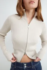 Sweater de punto celeste con diseño acanalado, cuello alto y cierre frontal con doble cremallera metálica, de manga larga y calce al cuerpo.