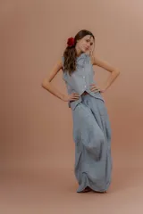 Pollera larga de lino color gris topo, de diseño amplio con volumen, movimiento y bolsillos delanteros. Cuenta con elástico en la cintura y detalles de pinzas y sobretelas en los laterales.