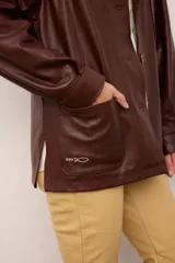 Chaquetón de cuero oversized color marrón, con corte recto, cuello camisero y cierre frontal de botones. Presenta bolsillos delanteros con bordados inspirados en la costa atlántica.