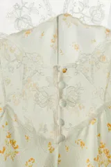 Mono corto de viscosa con estampado floral amarillo sobre fondo verde menta, escote cuadrado con detalles de encaje y tirantes finos.