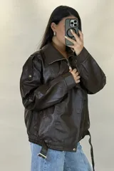 Chaqueta de ecocuero negro con diseño oversize, cuello solapa, cierre frontal y cinturón ajustable en el ruedo.