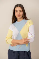 Sweater de punto de manga larga con diseño geométrico de rombos en tonos pasteles celeste, amarillo y blanco. Cuenta con cuello redondo y ribetes en el cuello, puños y ruedo.