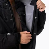 Campera técnica Merrell Ezeo 3-in-1 de color negro, diseñada para condiciones climáticas variables. Este sistema modular incluye una capa exterior impermeable con membrana 10K/10K, costuras termoselladas y tejido ripstop de poliéster reciclado, junto con una chaqueta interior insulada. Presenta capucha ajustable, ventilación axilar, codos preformados y múltiples bolsillos frontales.