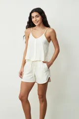 Musculosa color crudo con escote en V y botones frontales. Presenta un pequeño volante en el ruedo inferior.