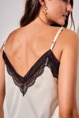 Blusa satinada marrón con detalles de encaje en el escote en V y en el ruedo. Presenta tirantes finos regulables.