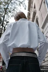 Camisa de popelín color blanco, con cuello solapa, manga larga y bajo abullonado con elástico interior. Cierre frontal con botones.