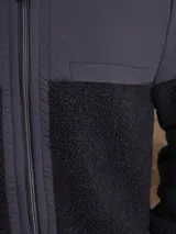 Campera con capucha confeccionada en una combinación de tejido técnico y sherpa, con cierre frontal completo y puños elásticos.