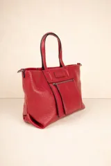 Cartera tipo tote bag de símil cuero texturizado color rojo, con asas fijas y correa larga desmontable y regulable. Posee un bolsillo exterior con cierre metálico y tres compartimientos internos.