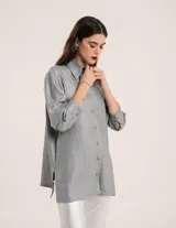 Camisa oversized con terminación metalizada color gris plomo. Tiene botones a tono en el delantero, largo por debajo de la cadera y tajos a los costados.