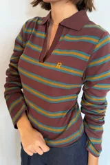 Remera polo de manga larga en tono marrón con rayas horizontales en verde y amarillo mostaza. Cuenta con cuello camisero, escote en V y un pequeño logo bordado en el pecho.
