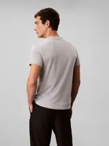 Remera gris melange de manga corta con cuello redondo, confeccionada en algodón regenerativo. Cuenta con un pequeño estampado gráfico del monograma y la inscripción de la marca en el pecho.