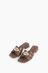 Sandalias de cuero color chocolate con taco bloque bajo, punta cuadrada y tiras cruzadas con detalle metálico dorado.