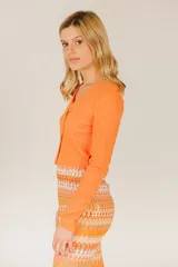 Top corto azul de tejido de punto acanalado, con mangas largas y cierre frontal con hebilla.