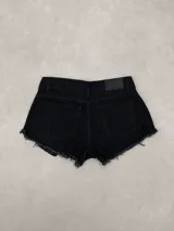 Short de jean negro de tiro bajo, con diseño clásico de cinco bolsillos, trabillas para cinto y bordes deshilachados.