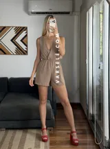 Mono corto negro con escote en V cruzado, sin mangas y con cinturón dorado.