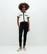 Pantalón skinny de tiro alto confeccionado en sarga de algodón con elastano. Presenta un diseño ajustado con bolsillos funcionales y detalle de botones decorativos en el ruedo.