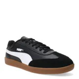 Championes urbanos Puma modelo 9T, con diseño inspirado en el fútbol sala. Presentan una combinación de cuero sintético negro en los laterales y gamuza negra en la puntera, con la icónica franja lateral de Puma en color blanco y suela de goma color caramelo.