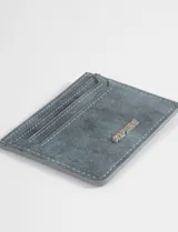 Tarjetero de cuero vegano con textura gamuzada, cuenta con ranuras para tarjetas y logo metálico de la marca en el frente.