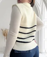 Chaleco de punto color crudo con rayas horizontales negras, cuello polo con cierre metálico y corte holgado.