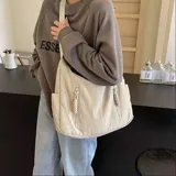 Bolso hobo grande color gris topo, de tela suave y liviana, con correa de hombro ajustable y dos bolsillos frontales con cierre.