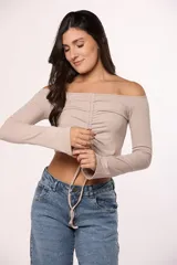 Top de algodón color marrón, con escote off-shoulder, mangas largas y detalle de frunce central con lazo ajustable.
