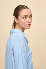 Camisa de calce relajado color celeste, con mangas 3/4, cuello clásico y cierre frontal con botones. Presenta detalles calados en el frente y en las mangas que aportan un acabado delicado al diseño.