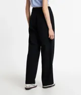 Pantalón de vestir negro, de corte recto, con cintura asimétrica y cierre por botón y cremallera.