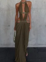 Vestido largo verde militar con escote halter profundo, recortes laterales y detalles brillantes en el cuello y la cintura.