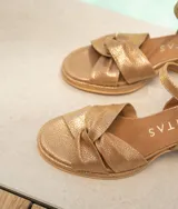 Sandalias de cuero color dorado, con plataforma y taco cuadrado. Presentan tiras cruzadas en el empeine y pulsera al tobillo con hebilla.