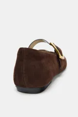 Bailarina plana confeccionada en ante color marrón, con diseño de punta cuadrada y cierre mediante una tira con hebilla metálica dorada en el empeine.