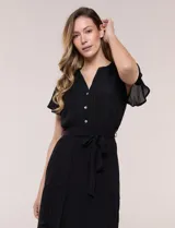 Vestido midi blanco de calce suelto y caída fluida, con escote en V, cuello a la base y apertura abotonada con detalle de puntilla. Cuenta con cintura elastizada con lazo para anudar a tono, mangas cortas con volados y falda con volantes escalonados.