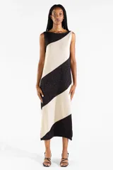 Vestido midi tejido bicolor en negro y beige con brillo sutil, escote bote, diseño sin mangas y abertura lateral en el dobladillo.