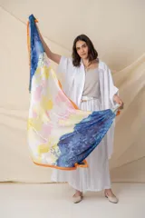 Pañuelo cuadrado de seda con estampado abstracto en degrade de colores azul, amarillo, blanco y rosa, con borde naranja.